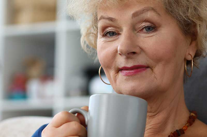 Older woman sipping tea and smiling